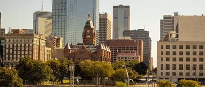 The Dallas skyline featuring modern corporate skyscrapers rising behind historic red brick architecture.
