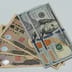 A close-up view of United States one hundred dollar bills resting on top of Japanese ten thousand yen notes.