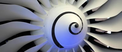 Close-up of a modern jet engine turbine with pristine white blades and a spiral center.