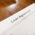 A close-up view of a printed loan agreement document resting on a wooden table.