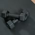 A pair of identical black dumbbells resting on a textured black gym mat.