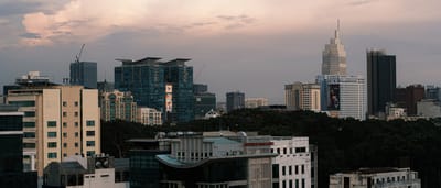 The modern, illuminated skyline of Ho Chi Minh City, Vietnam reflects on the river at dusk.