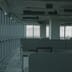 A quiet, empty modern office space with rows of vacant desks and large windows facing a grey sky.