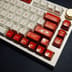 A close-up of a custom mechanical keyboard featuring prominent red Backspace and Delete keys.